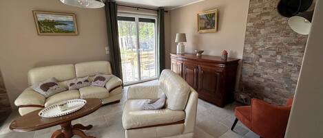 A living room with a sofa, armchair, and a table with a tray. There is a cabinet and a wall with a textured pattern.
