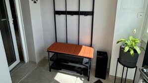 Una habitación pequeña y luminosa con un banco, una planta en maceta y un radiador.