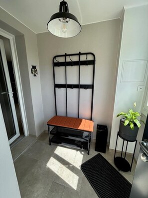 A small, well-lit room with a bench, a potted plant, and a radiator. - Le Chaumet - SAINT-DENIS-EN-MARGERIDE (SAINT-DENIS-EN-MARGERIDE)