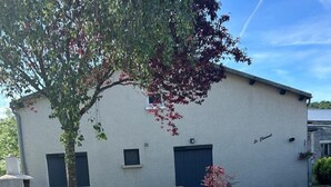 Un edificio de fachada blanca, una banca y un árbol en su parte frontal.