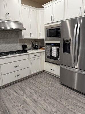 A modern kitchen with white cabinetry, stainless steel appliances, and a wood-patterned floor. - Perfect 4-bedroom home in Reunion Village West Kissimmee (Kissimmee)