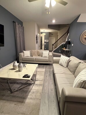 A living room with a sectional sofa, a coffee table, and a staircase leading to another level. - Perfect 4-bedroom home in Reunion Village West Kissimmee (Kissimmee)