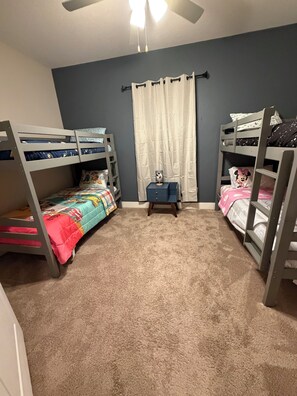 A room with two bunk beds, a small table, and a ceiling fan. - Perfect 4-bedroom home in Reunion Village West Kissimmee (Kissimmee)