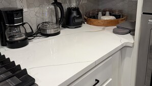 Ett kök med vita skåp, en kaffebryggare, en mixer och en brödrost.