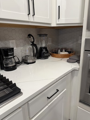 Eine Küche mit weißen Schränken, einer Kaffeemaschine, einem Mixer und einem Toaster.