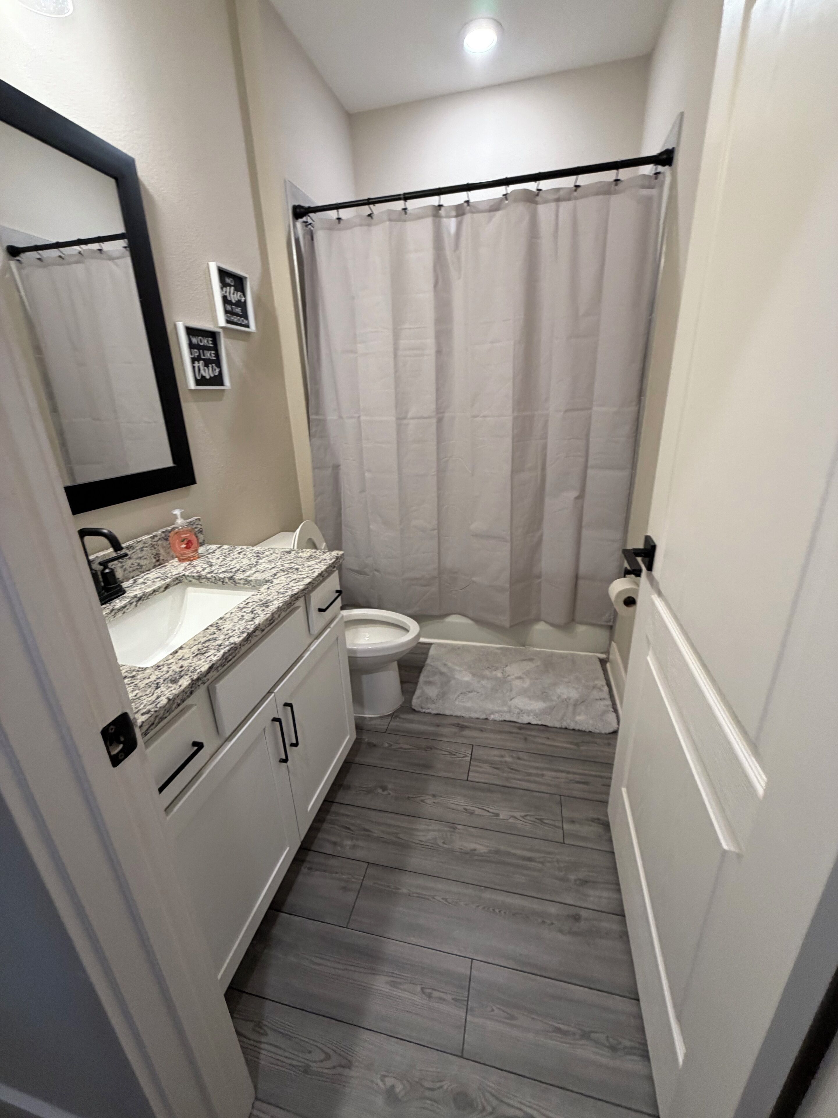 A bathroom with a white sink, toilet, and shower curtain.