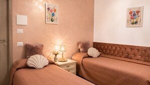 Une chambre d’hôtel avec deux lits, une table de chevet avec une lampe et deux tableaux accrochés au mur.