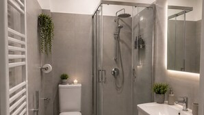 Une salle de bain moderne avec une douche à parois de verre, des toilettes, un lavabo et un miroir.