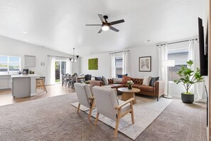 Ein geräumiger Wohnbereich mit Sofa, Sesseln, einem Couchtisch und einem Deckenventilator.