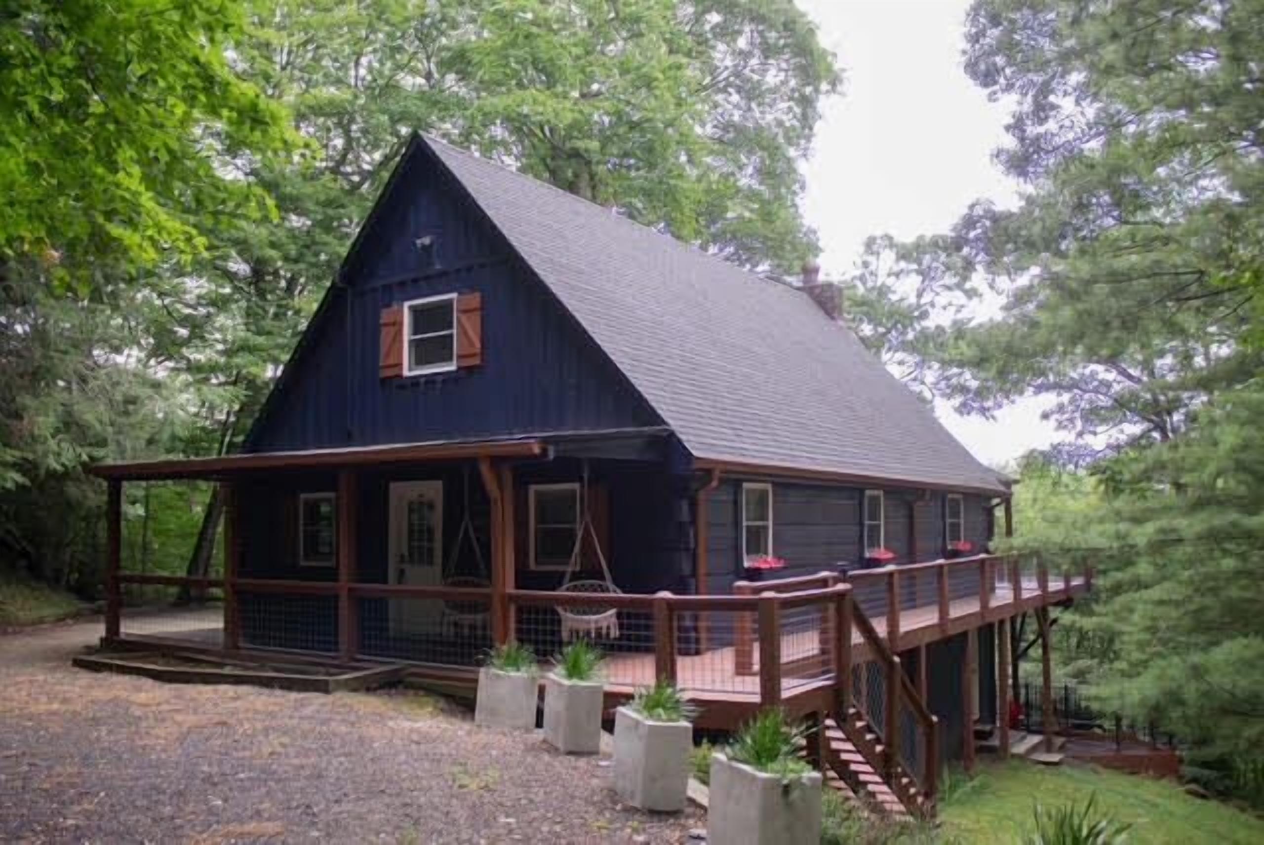 Une cabane en bois avec un porche, entourée d’arbres.