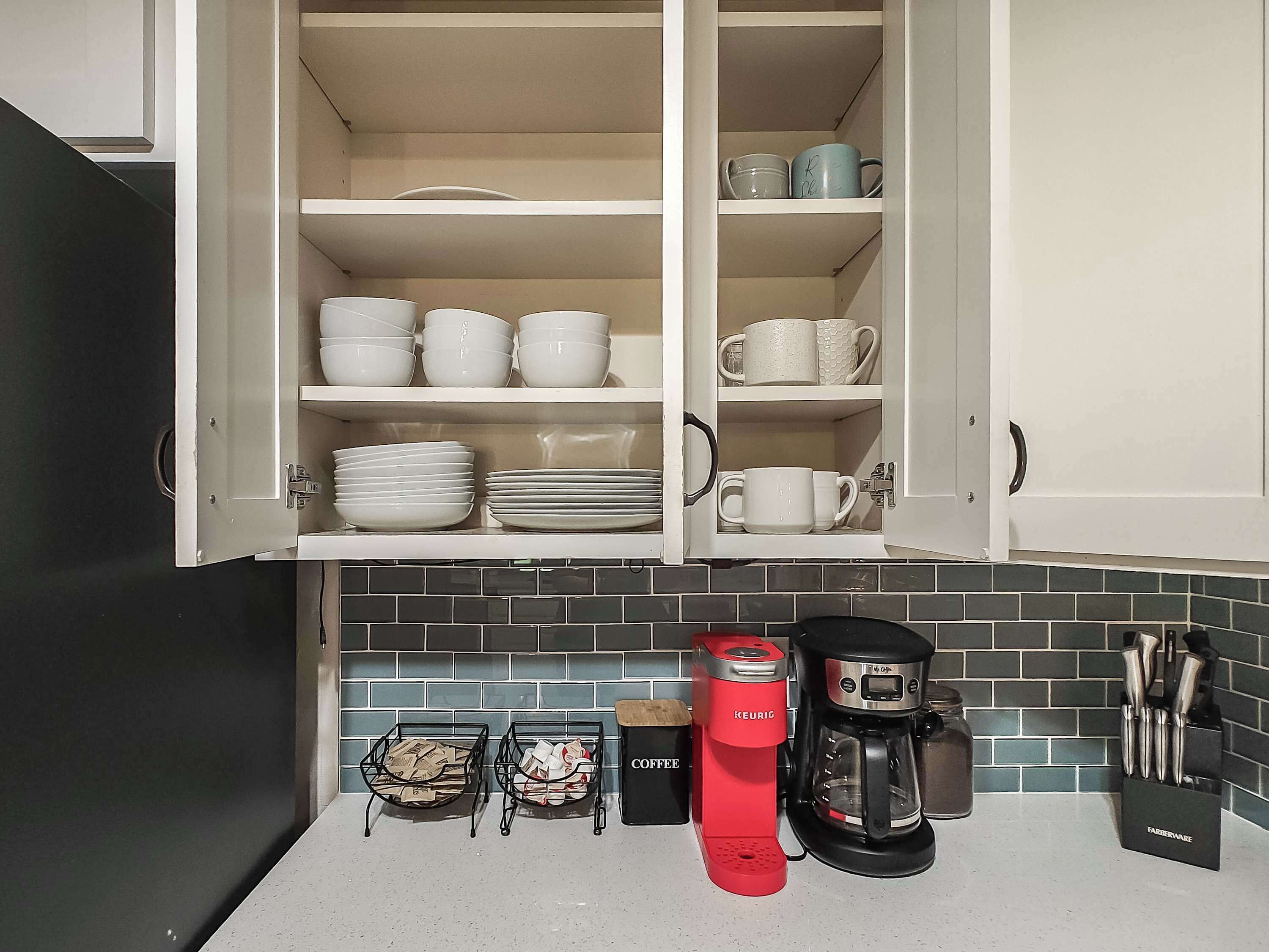 Uma cozinha com armários brancos, cafeteira e suporte para facas.
