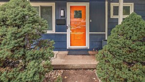 A house with a blue exterior, a bright orange door, and a small porch with a black mat. - 4 Bdrm Getaway with Hot Tub (Overland Park)