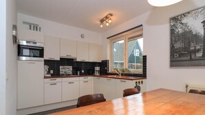 Een moderne keuken met witte kastjes, een houten eettafel en een raam met uitzicht op een huis.