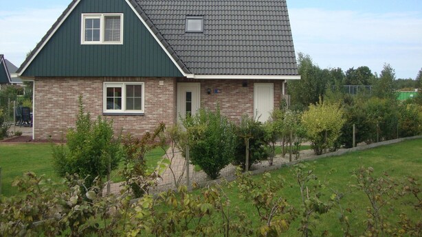 Een herenhuis met twee verdiepingen, een puntgevel, een bakstenen gevel en een klein voortuintje.