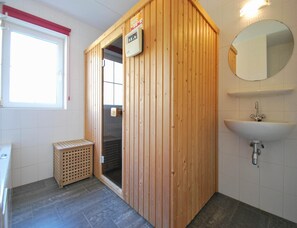 A wooden sauna with a control panel, a small wooden bench, a sink, and a mirror. - 6-guest Deluxe Beach Villa With Sauna (Makkum)