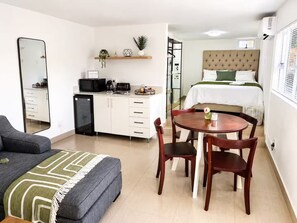 A compact hotel room with a kitchenette, a dining area, a bed, and a large mirror. - The Lighthouse Suite Umhlanga (uMhlanga)