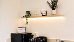 Eine Küche mit Kaffeemaschine, Toaster und einem Regal mit Pflanze und Kerzen.