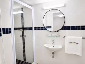 A bathroom with a glass-enclosed shower, a white sink, and a towel rack with a towel labeled 'LIGHTHOUSE Suite'. - The Lighthouse Suite Umhlanga (uMhlanga)