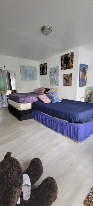 Une chambre avec deux lits, un luminaire au plafond et diverses œuvres d’art murales.