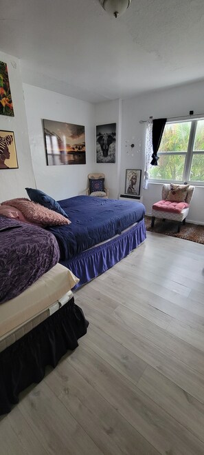 Un dormitorio con dos camas, una ventana con cortinas y decoración en la pared.