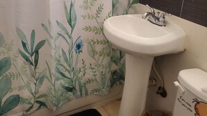 Et badeværelse med en hvid vask, toilet og bruseforhæng med blomstermønster.