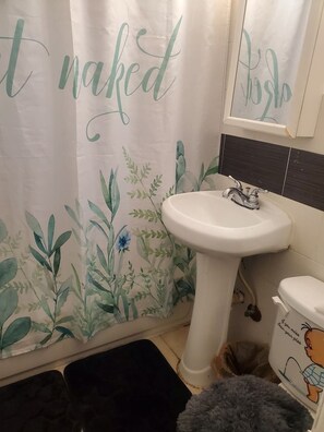 Un baño con lavamanos blanco, inodoro y cortina de ducha con estampado floral.