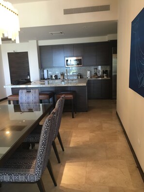 A modern kitchen with dark cabinets, a stainless steel microwave, and a granite countertop. - Posh 2-bedroom condo in charming Cabo with AC, kitchen and 2.5 baths.Ocean view. (Cabo San Lucas)