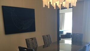 A dining area with a large rectangular table, patterned chairs, a modern chandelier, and a large abstract painting on the wall. - Posh 2-bedroom condo in charming Cabo with AC, kitchen and 2.5 baths.Ocean view. (Cabo San Lucas)