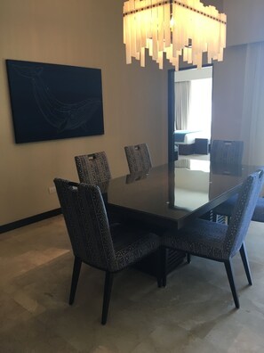A dining area with a large rectangular table, patterned chairs, a modern chandelier, and a large abstract painting on the wall. - Posh 2-bedroom condo in charming Cabo with AC, kitchen and 2.5 baths.Ocean view. (Cabo San Lucas)