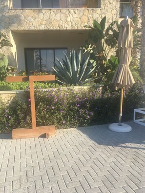 A paved area with a wooden bench, a potted plant, and an umbrella stand. - Posh 2-bedroom condo in charming Cabo with AC, kitchen and 2.5 baths.Ocean view. (Cabo San Lucas)