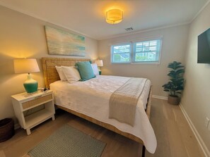 A bedroom with a bed, bedside lamps, a painting, a window, and a potted plant. - Perfect Peaceful Shore Getaway! Close to beach, private yard, off street parking (Mantoloking)