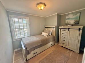 A bedroom with a bed, a dresser, a window with blinds, and a ceiling light fixture. - Perfect Peaceful Shore Getaway! Close to beach, private yard, off street parking (Mantoloking)