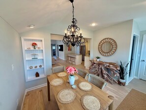 A dining area with a wooden table, woven placemats, and a chandelier. - Perfect Peaceful Shore Getaway! Close to beach, private yard, off street parking (Mantoloking)