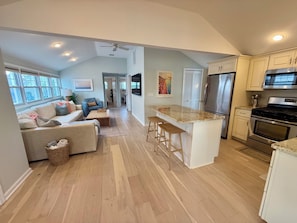 A modern kitchen with a central island, stainless steel appliances, and a dining area with a sofa and coffee table. - Perfect Peaceful Shore Getaway! Close to beach, private yard, off street parking (Mantoloking)