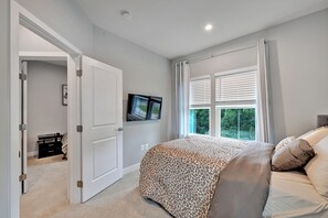 A bedroom with a bed, a television mounted on the wall, and a window with blinds. - Exquisitely finished 3-bedroom Townhome on 3-levels with 2-car garage. (Glenarden)