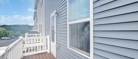 Un immeuble résidentiel doté d’une terrasse en bois, de balustrades blanches et d’une grande fenêtre.