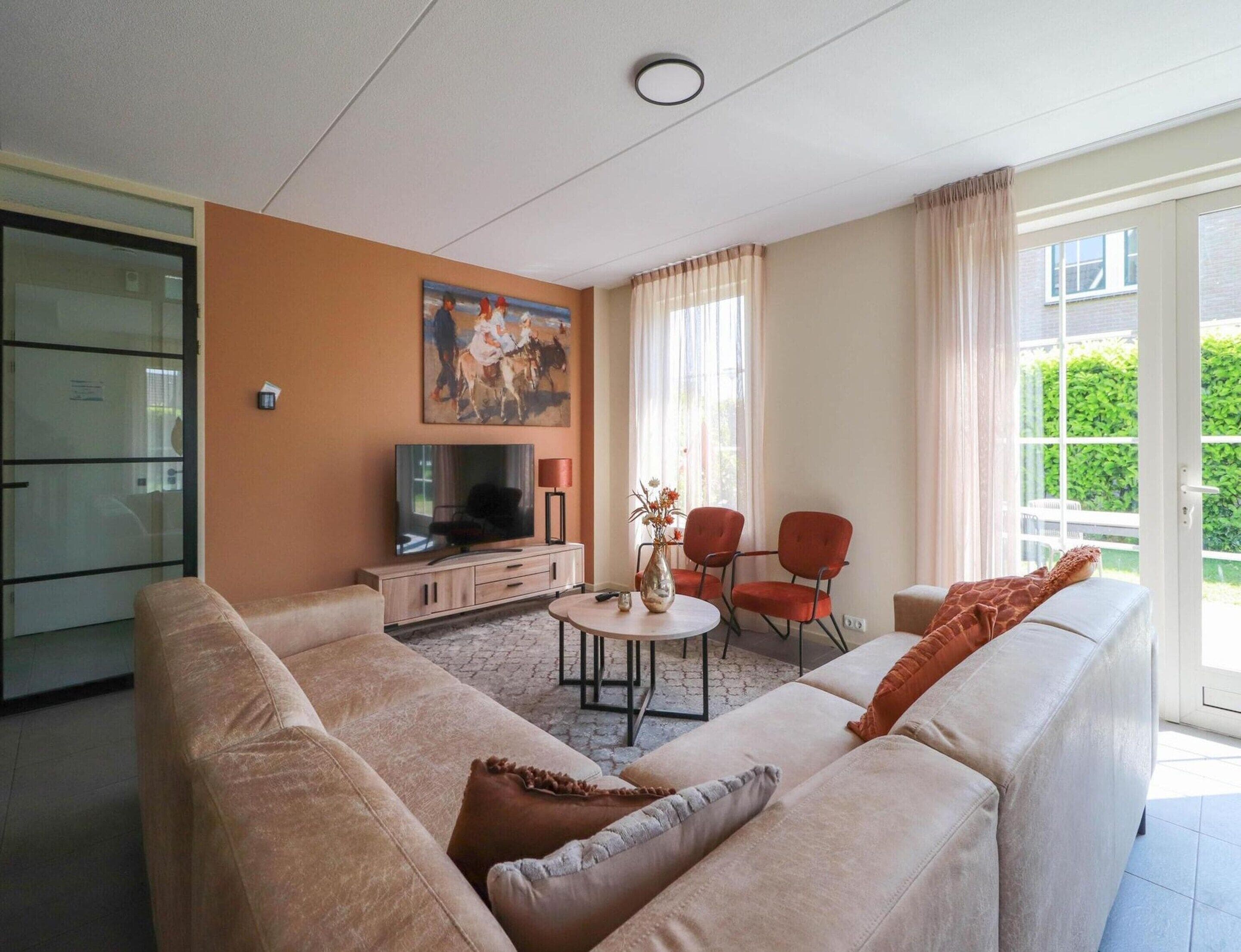 A living room with a sofa, a TV, a coffee table, and a painting on the wall.