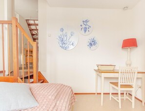 A bedroom with a bed, a desk with a chair, a lamp, and a staircase. - Panoramic Villa With Sauna & Lake Views (Makkum)