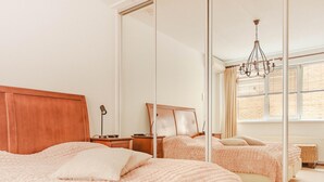A bedroom with a large mirror, a wooden headboard, a chandelier, and a view of the outside through the window. - Panoramic Villa With Sauna & Lake Views (Makkum)