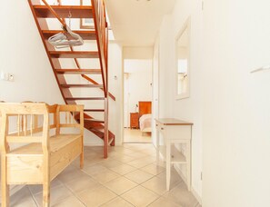 Una escalera conduce a un dormitorio con una cama, una mesita de noche y un espejo en la pared.