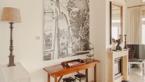 A room with a large black and white photograph on the wall, a wooden console table, a lamp, and a mirror. - Panoramic Villa With Sauna & Lake Views (Makkum)
