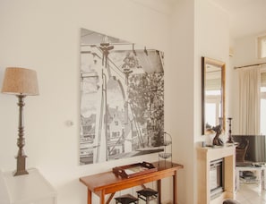 A room with a large black and white photograph on the wall, a wooden console table, a lamp, and a mirror. - Panoramic Villa With Sauna & Lake Views (Makkum)