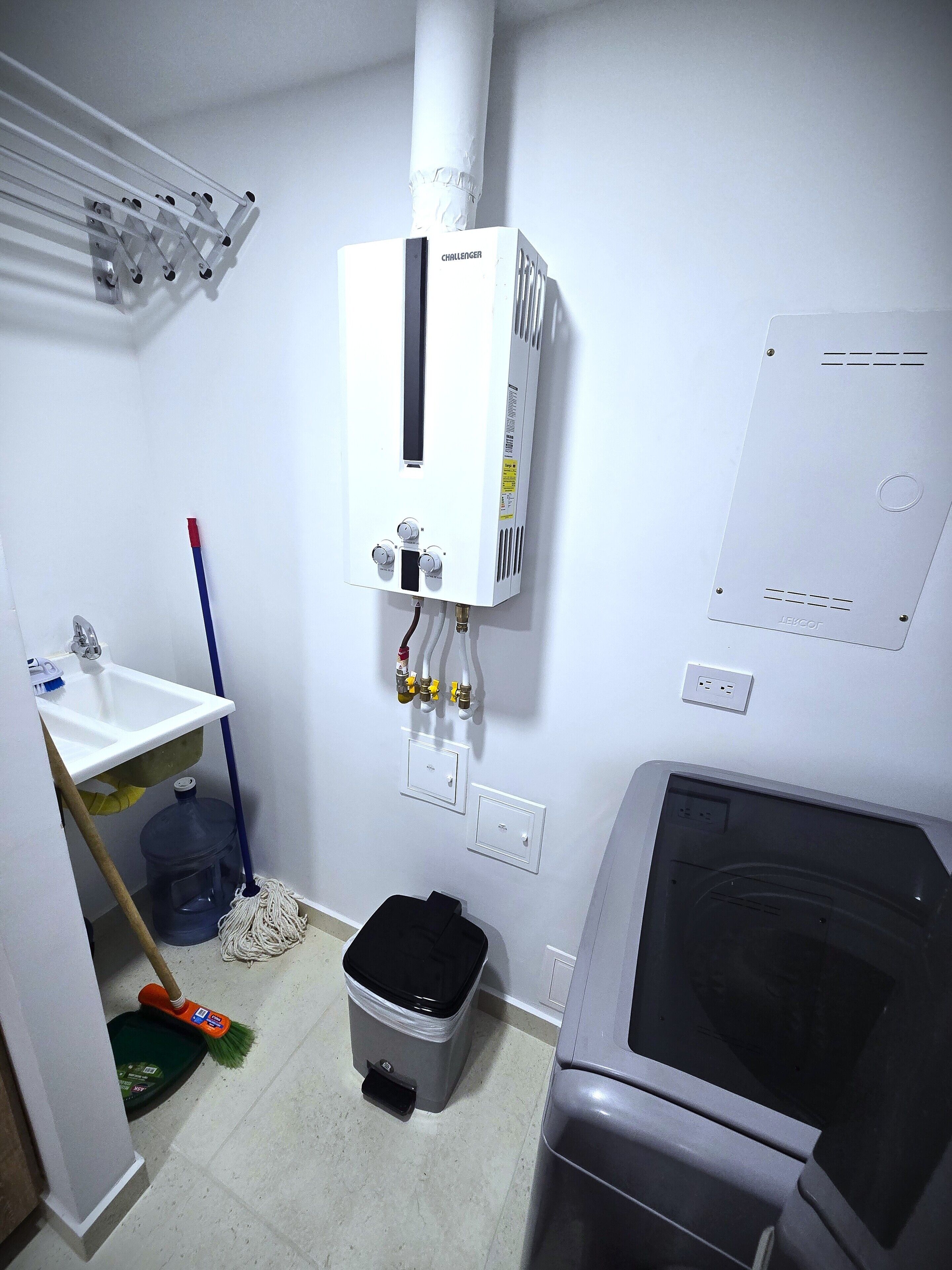 Une salle de bain avec un radiateur blanc, un lavabo, une serpillière, une poubelle et un espace douche.