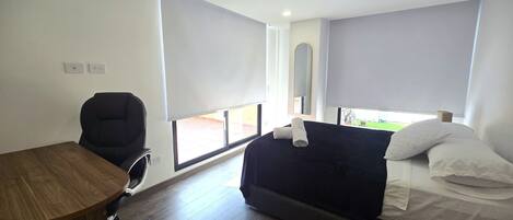 A room with a bed, a desk, a chair, and a window.