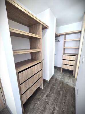 Ein begehbarer Kleiderschrank mit Holzböden und Schubladen.