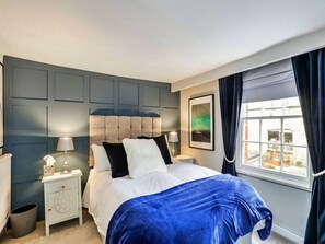 A bedroom with a bed, bedside tables, a window with curtains, and a view of the outside. - Luxury Stone Painswick Retreat for 6 (Stroud)