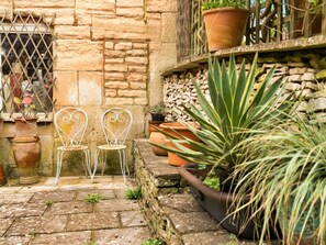 A stone building with two white metal chairs in front of a window with a metal grill. - Luxury Stone Painswick Retreat for 6 (Stroud)