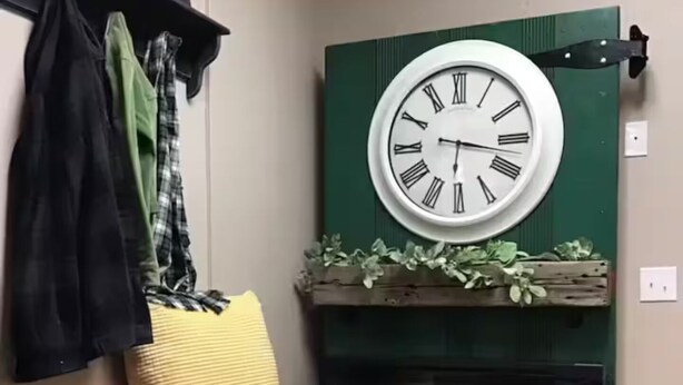 Een kamer met een houten bank, een wandklok en een open haard met een groene schouw.