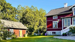 A red house with a white porch and a small shed. - 4 Star Holiday Home in Osthammar (Osthammar)