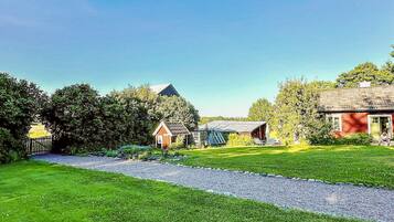 A rural property with a gravel path, a red barn, and a small wooden structure.